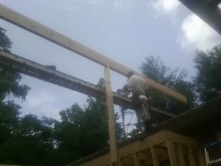 Carpenter setting a ridge beam over a new addition frame — Ice Dam Removal by Roofing Brothers in Le Center