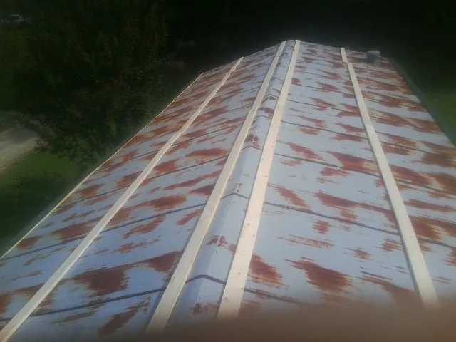 Rusted metal roof panels with new wood purlins before replacement — Storm Damage Roof Repair in Le Center by Roofing Brothers
