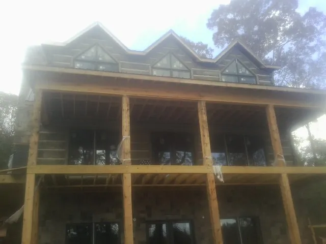 Dormers and porch framing on a large log home under construction — Roof Coating work by our crew in Le Center