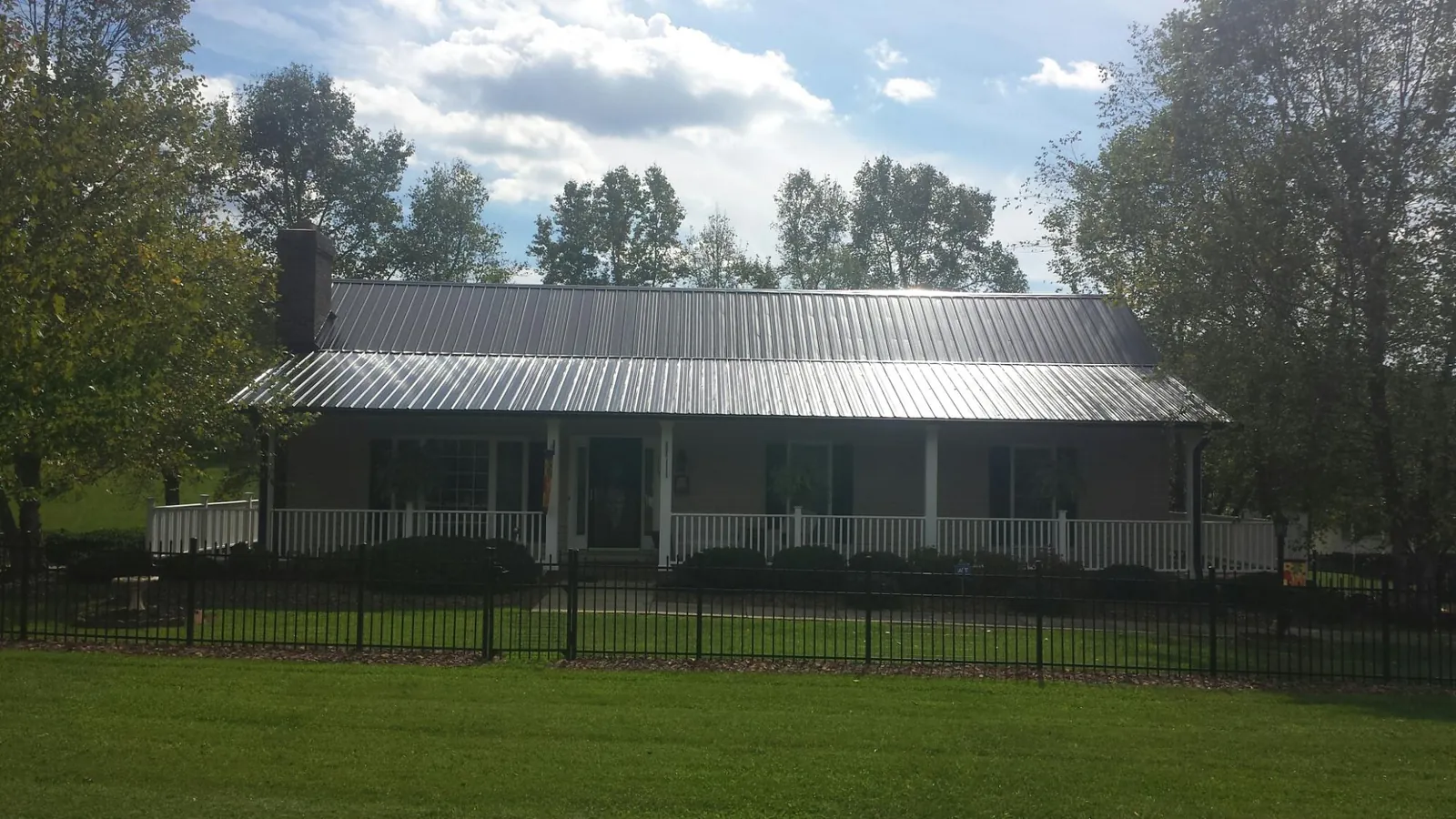Gray metal roof on a brick ranch with a full width front porch — Gutter Guard Installation work by our crew in Le Center
