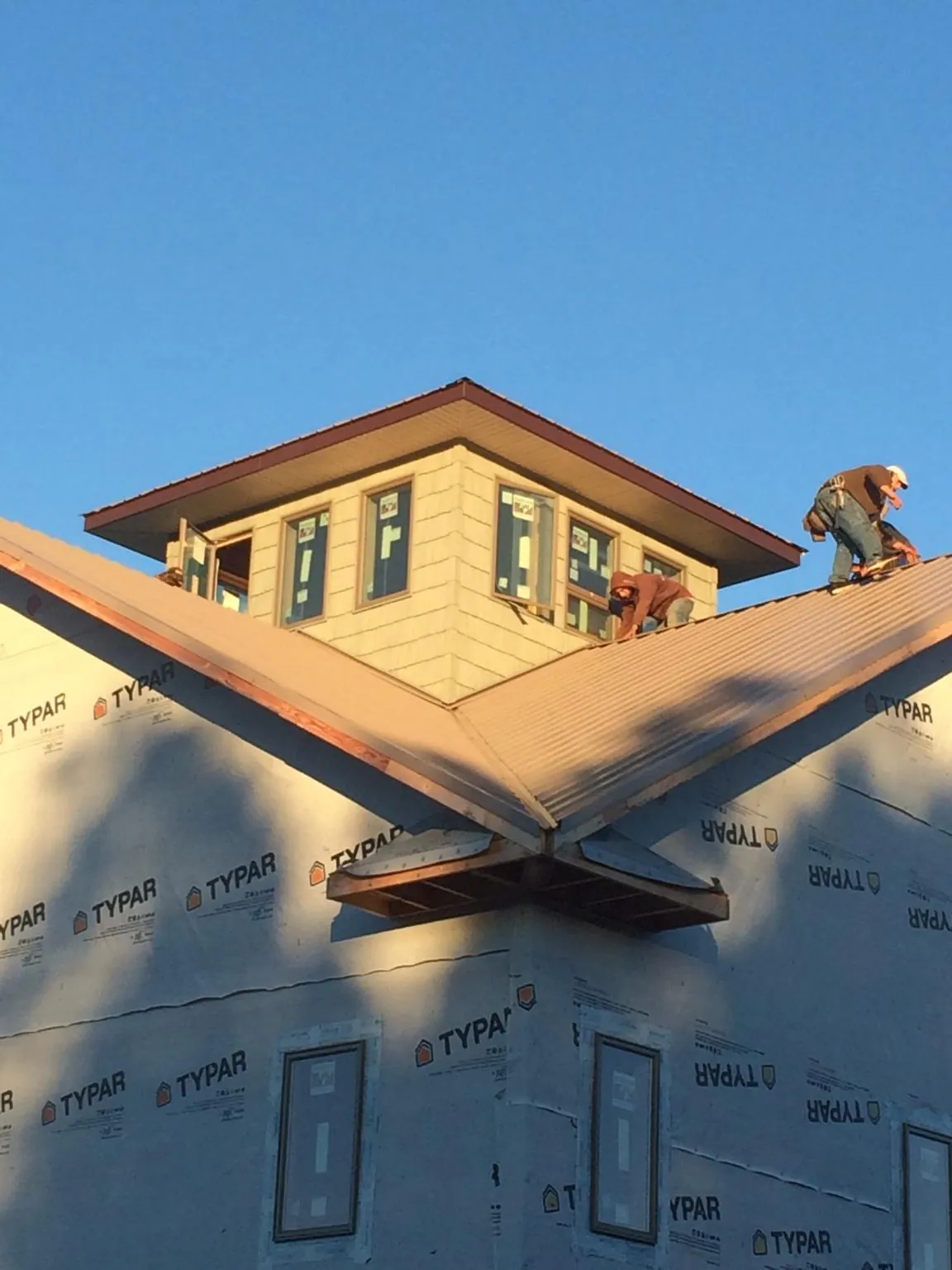 Roofers working around a rooftop cupola on a new metal roof at sunset — Roof Waterproofing in Le Center by Roofing Brothers